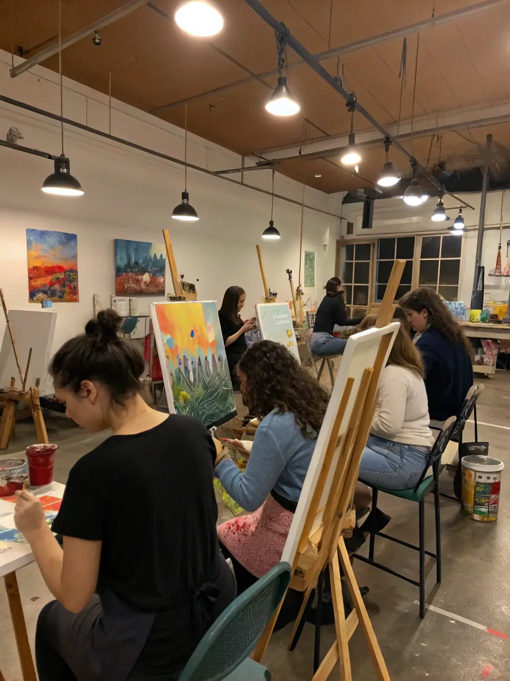 A photograph capturing artists deeply engaged in a collaborative painting session during an artistic residency at ROCS ET SOURCES, showcasing the creative process and community interaction.